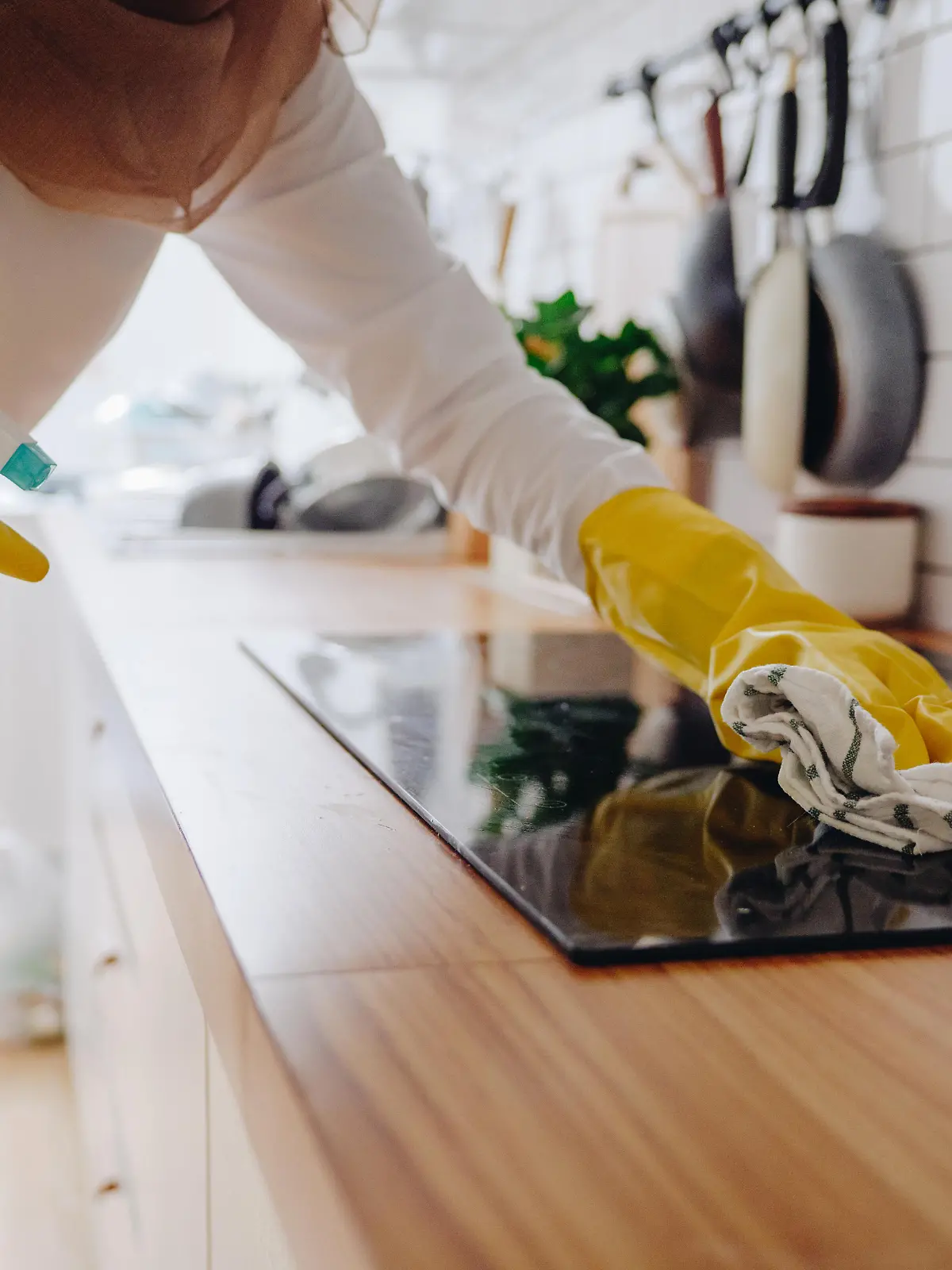 Young muslim woman cleaning modern cooking glass ceramic electric surface with sponge and detergent