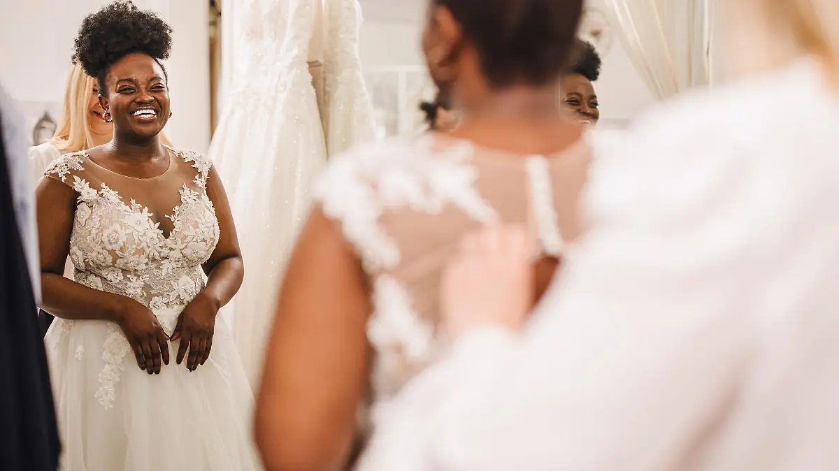 The future bride looks around the shop and tries on wedding dresses in the presence of her best friends. Lifestyle shopping concept, post-Covid-19 era