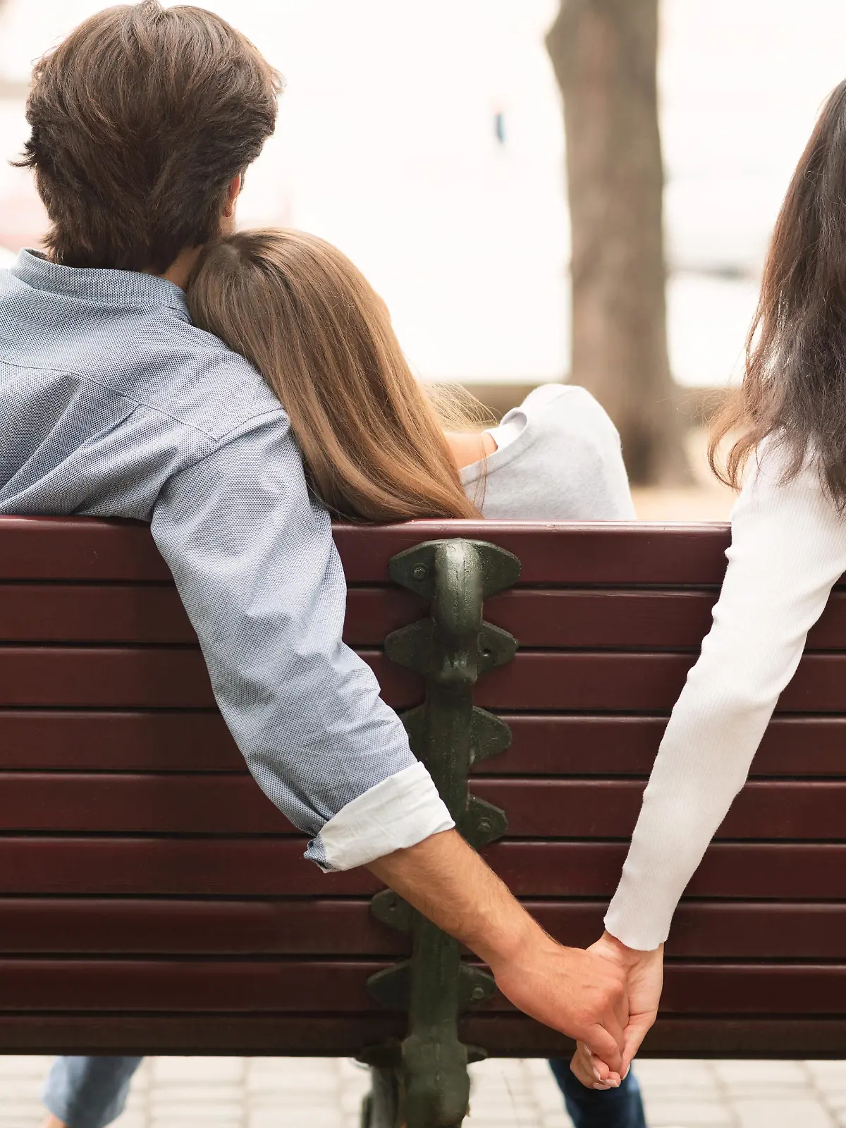 Love Triangle. Cheating Boyfriend Hugging Girlfriend Holding Hands With Her Girl Friend Sitting On Bench Together In Park Outdoor. Back-View