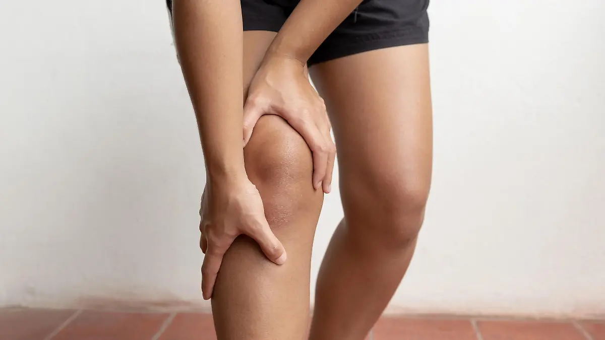 Woman hand massage physiotherapy her knee is sore and numb, exhausted, tingling. Guillain-Barre Syndrome, a side effect of the Covid vaccination.