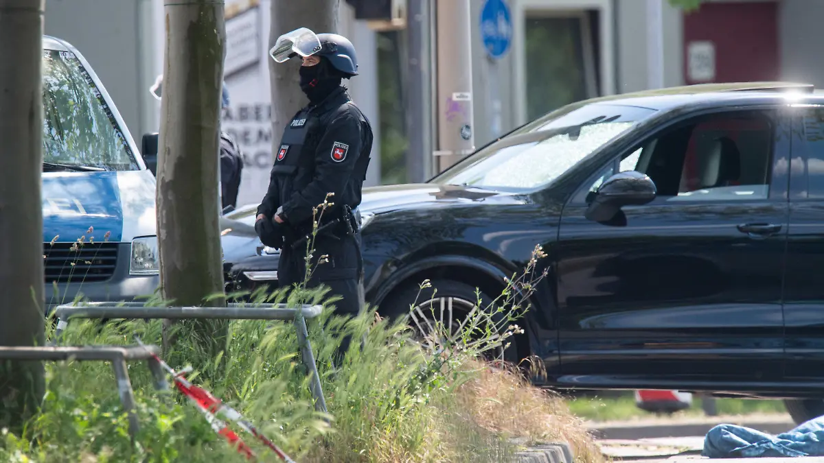ARCHIV - 03.06.2021, Niedersachsen, Hannover: Polizisten sichern einen Tatort in Hannover, wo neben einem Auto eine abgedeckte Person liegt. Bei einer Auseinandersetzung zwischen Insassen von zwei PKW wurde ein Mann getötet. (zu dpa: «Prozessbeginn nach tödlichem Schuss auf Autofahrer») Foto: Julian Stratenschulte/dpa +++ dpa-Bildfunk +++