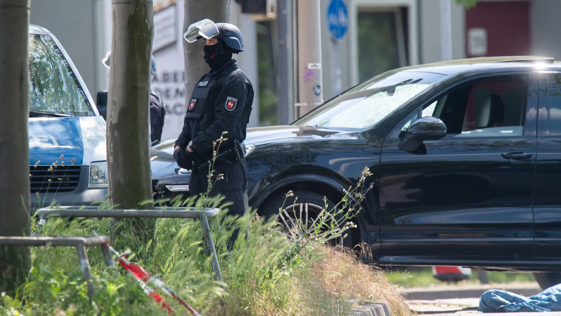 ARCHIV - 03.06.2021, Niedersachsen, Hannover: Polizisten sichern einen Tatort in Hannover, wo neben einem Auto eine abgedeckte Person liegt. Bei einer Auseinandersetzung zwischen Insassen von zwei PKW wurde ein Mann getötet. (zu dpa: «Prozessbeginn nach tödlichem Schuss auf Autofahrer») Foto: Julian Stratenschulte/dpa +++ dpa-Bildfunk +++
