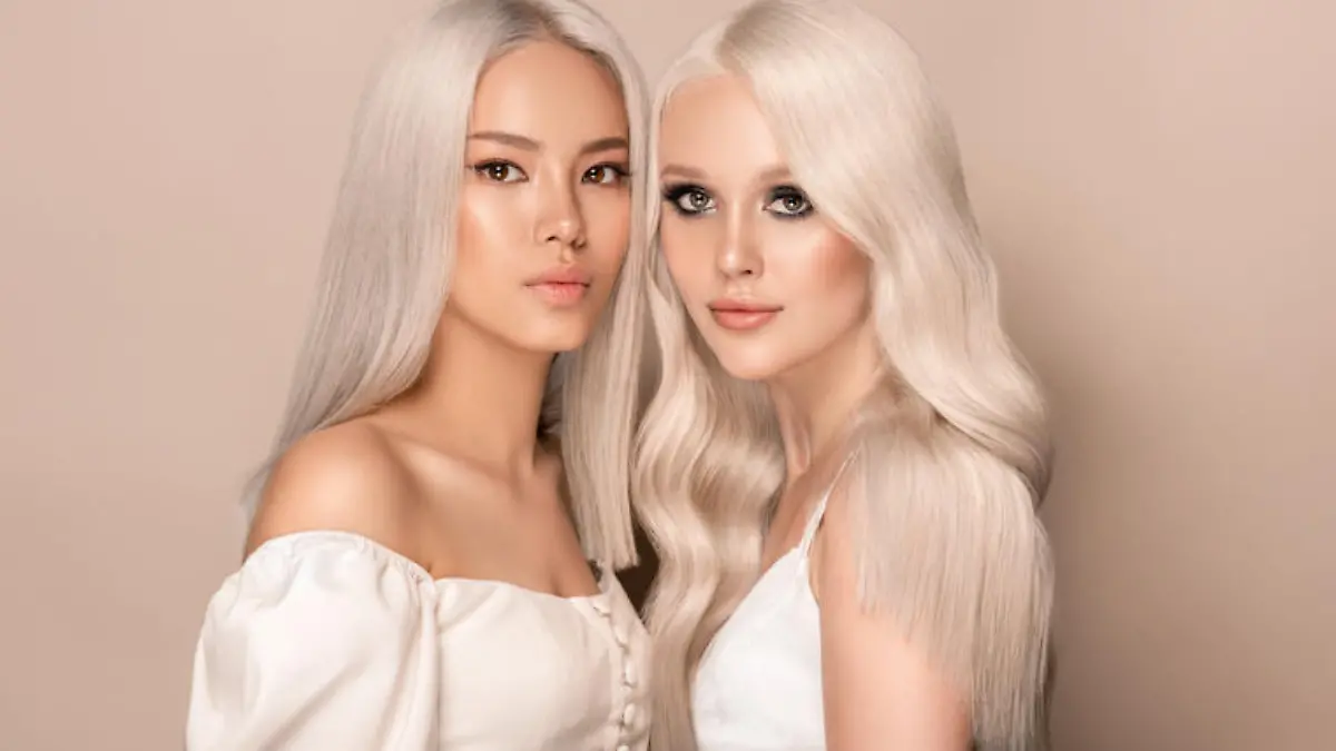 Double portrait of young attractive models with dyed blonde hairstyle. Group portrait of blondes with long, well cared hair. Sensual looks and elegant makeup. Coloration in blonde. Stylish blonde hair.Hairdressing art.