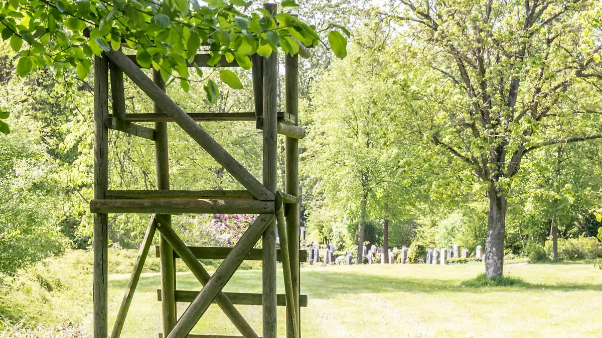 Ein Hochsitz vor vielen Gräbern auf einem Friedhof.