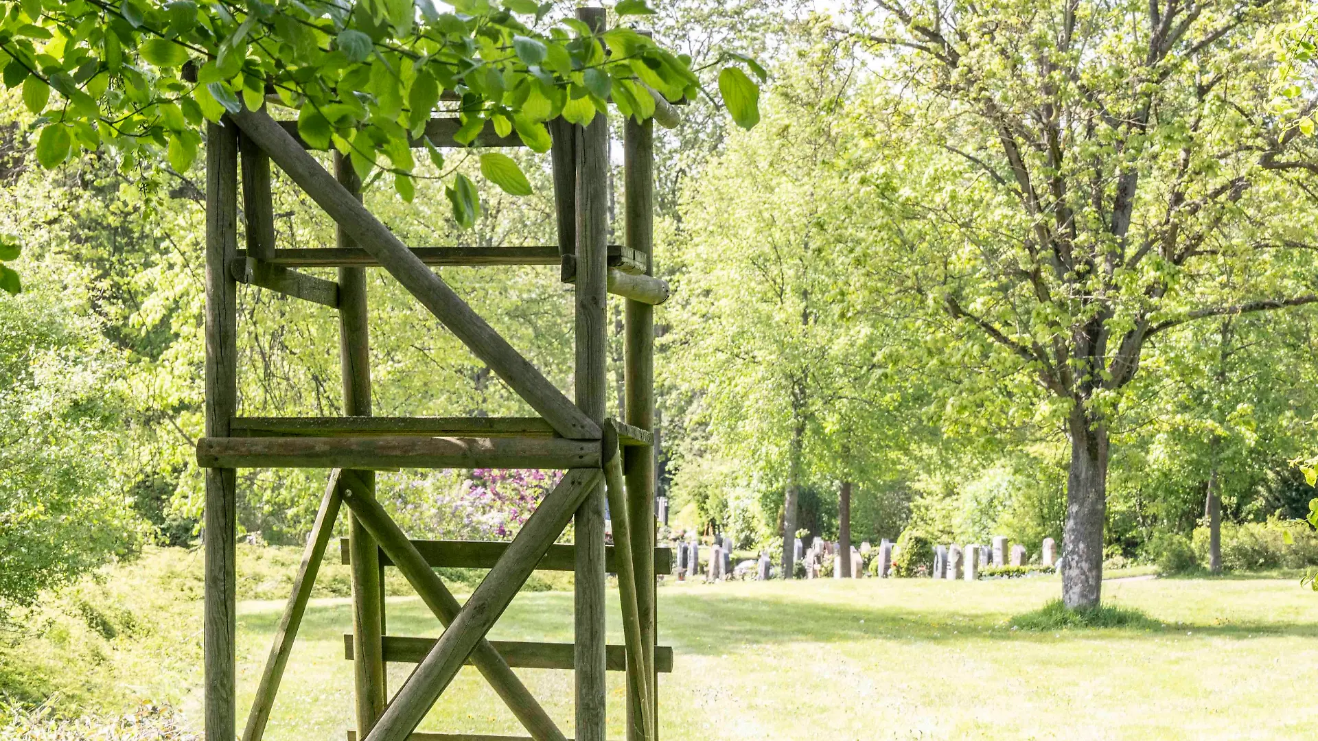 Ein Hochsitz vor vielen Gräbern auf einem Friedhof.