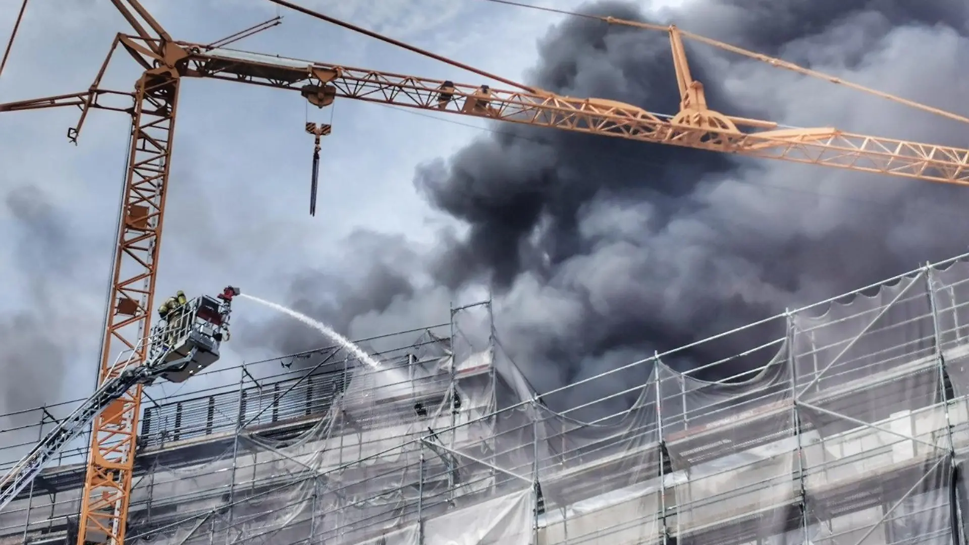 20.05.2022, Baden-Württemberg, Heidelberg: Einsatzkräfte der Feuerwehr löschen von einer Drehleiter aus den Brand auf einer Baustelle. Rund 30 Menschen brachten sich am Freitag nach Angaben einer Polizeisprecherin in Sicherheit. (zu dpa «Gebäude in Heidelberg brennt - 30 Menschen retten sich ins Freie») Foto: Marvin Riess/Einsatz-Report24/dpa +++ dpa-Bildfunk +++