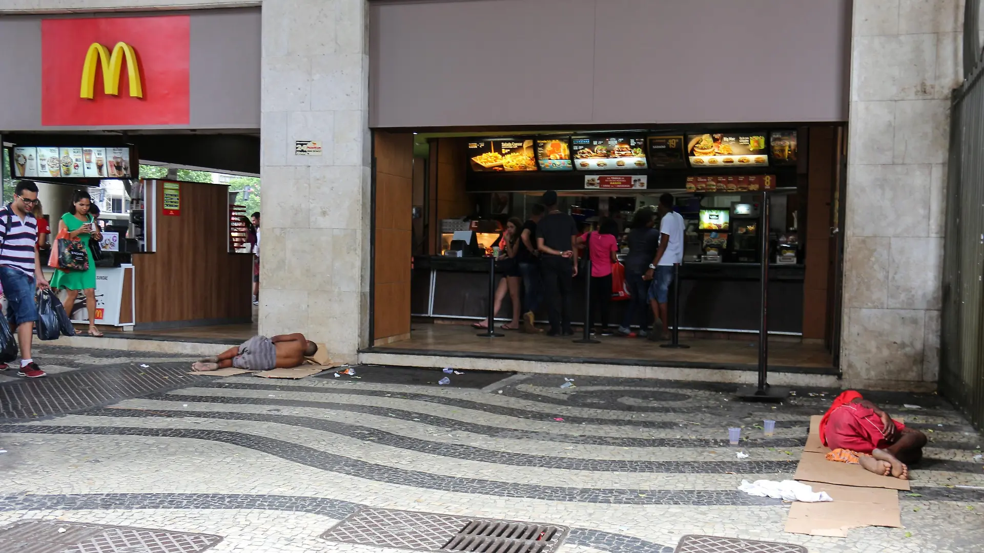 Social inequality has increased more and more in Rio de Janeiro, Brazil on December 24, 2016. On Christmas Eve, a group of homeless people slept in front of a McDonald's store while children played with what they had. People passed the place indifferently to the scene while they were shopping. (Photo by Luiz Souza/NurPhoto)