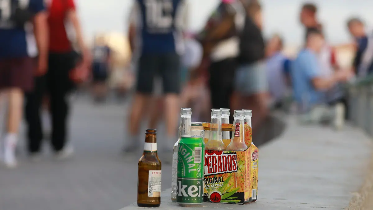 ARCHIV - 09.06.2023, Spanien, Palma: Menschen haben sich am Abend an der Promenade am Strand von Arenal versammelt. Auf einer Balustrade stehen mehrere leere Flachen alkoholischer Getränke.  (Zu dpa: «Mallorca läutet die Partysaison ein») (zu dpa: «Mallorca läutet die Partysaison ein») Foto: Clara Margais/dpa +++ dpa-Bildfunk +++