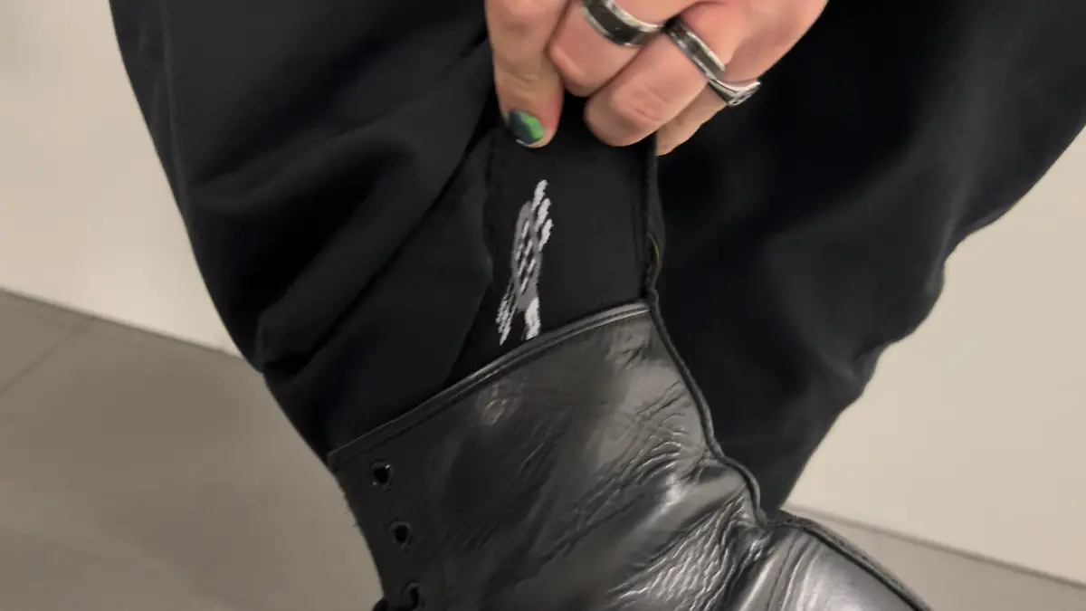 Isaak Guderian zeigt seinen linken Strumpf. Auf der schwarzen Socke ist ein weißes Gitarrenmotiv zu sehen.