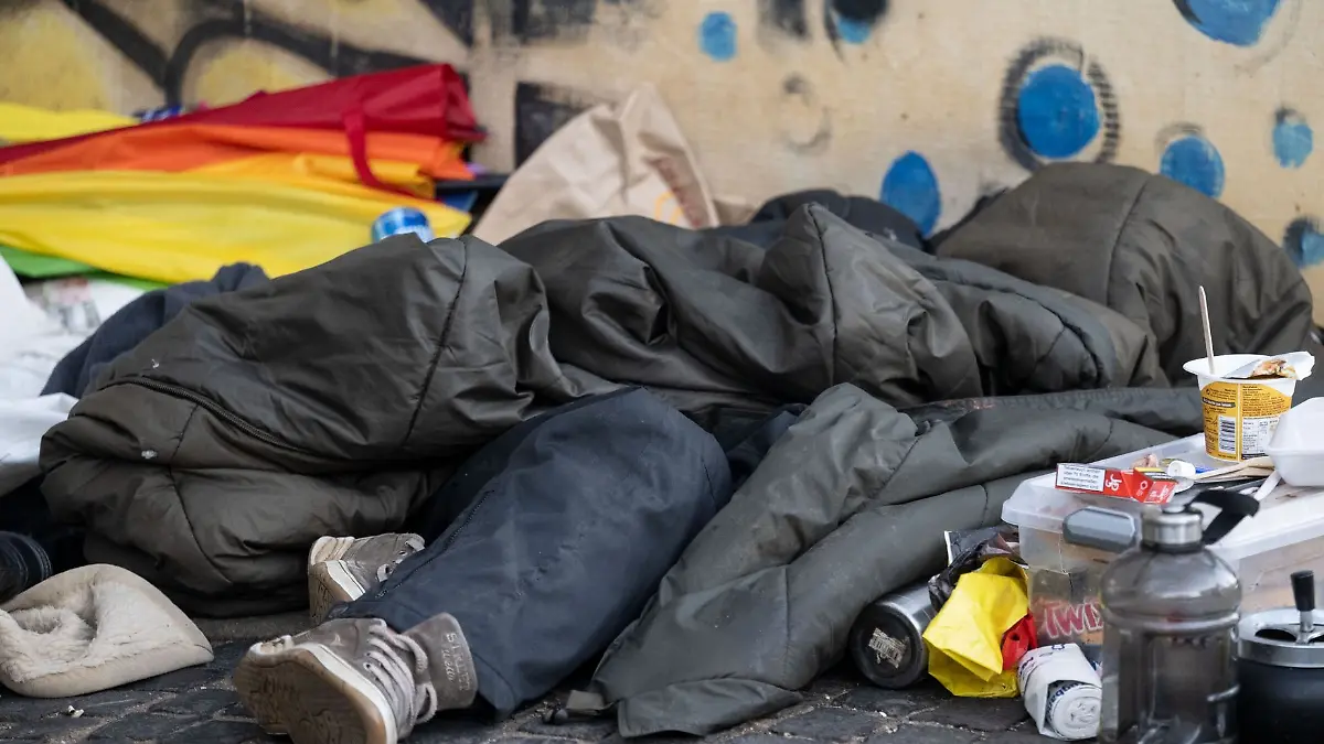 Eine Person liegt in der Innenstadt unter einem Schlafsack.