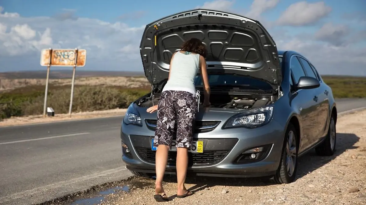 ILLUSTRATION - Ein Frau schaut am 13.10.2015 an einer Strasse bei Sagres (Portugal) in den geoeffneten Motorraum ihres Mietwagens (gestellte Szene). Foto: Florian Schuh
