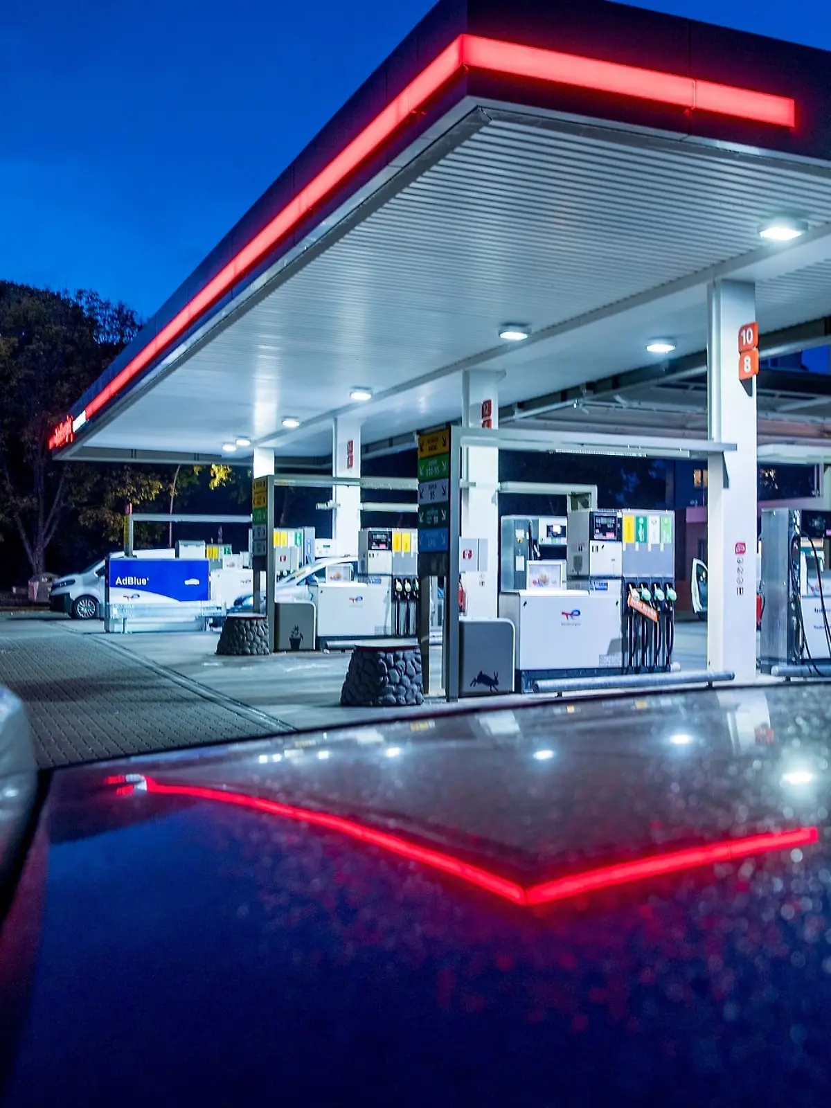 Autos stehen abends vor einer Tankstelle.