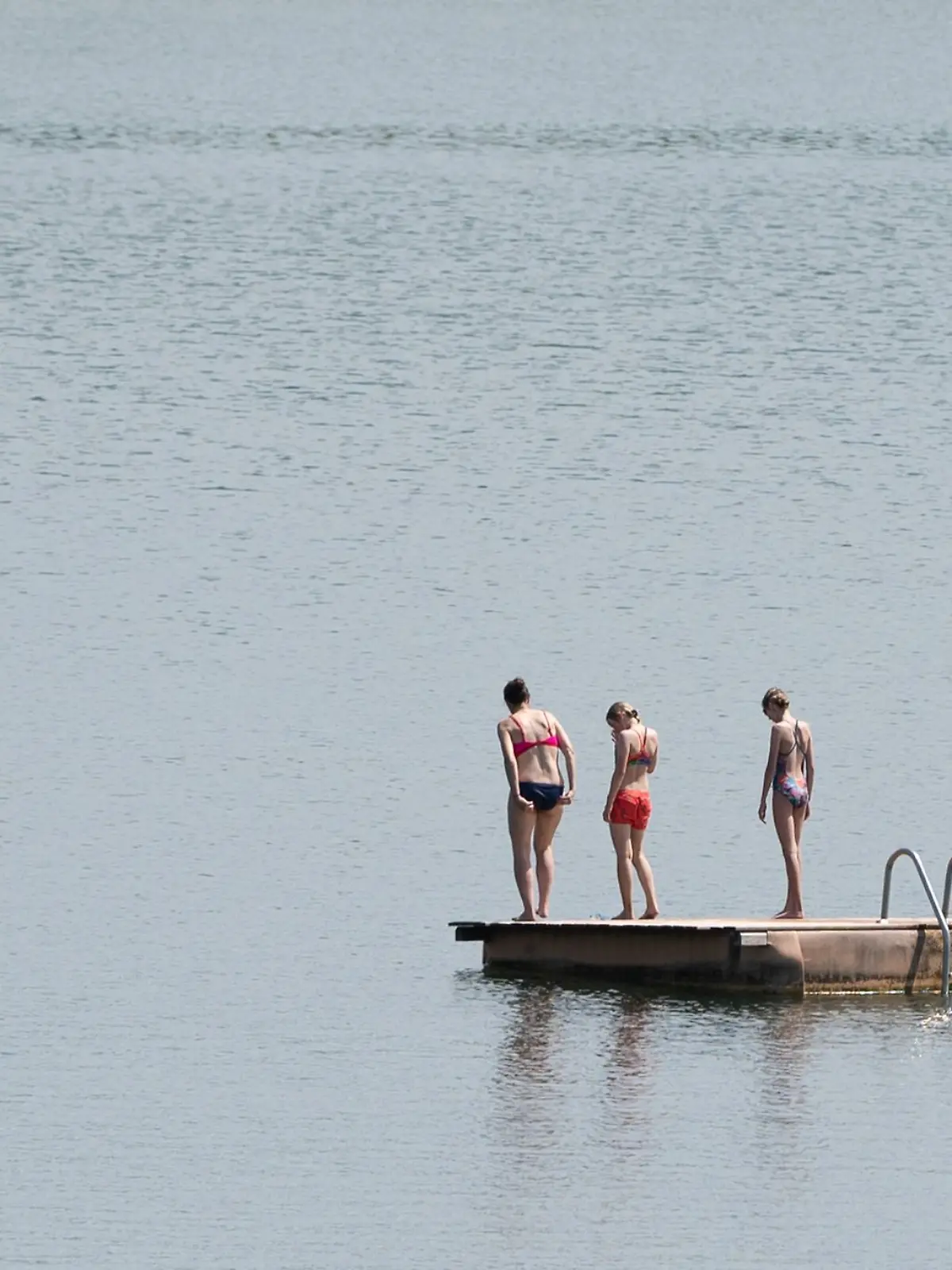 Badegäste stehen im Badesee Birkwitz auf einer Badeinsel.