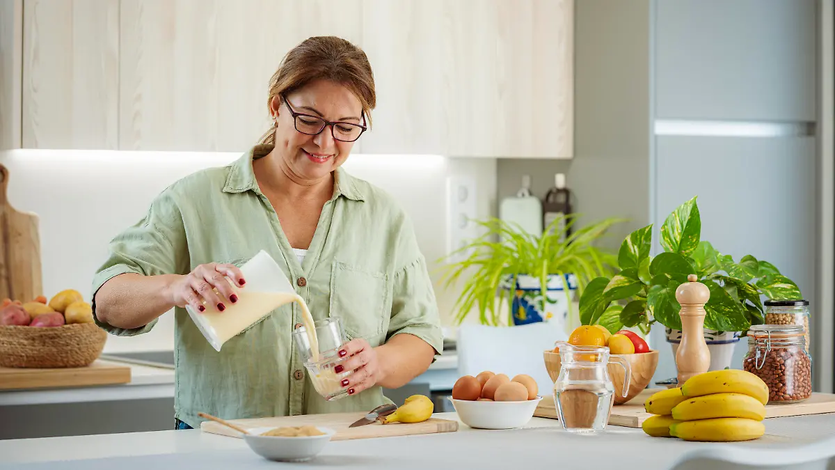 Mature woman pouring fresly blended protein and fruits drink