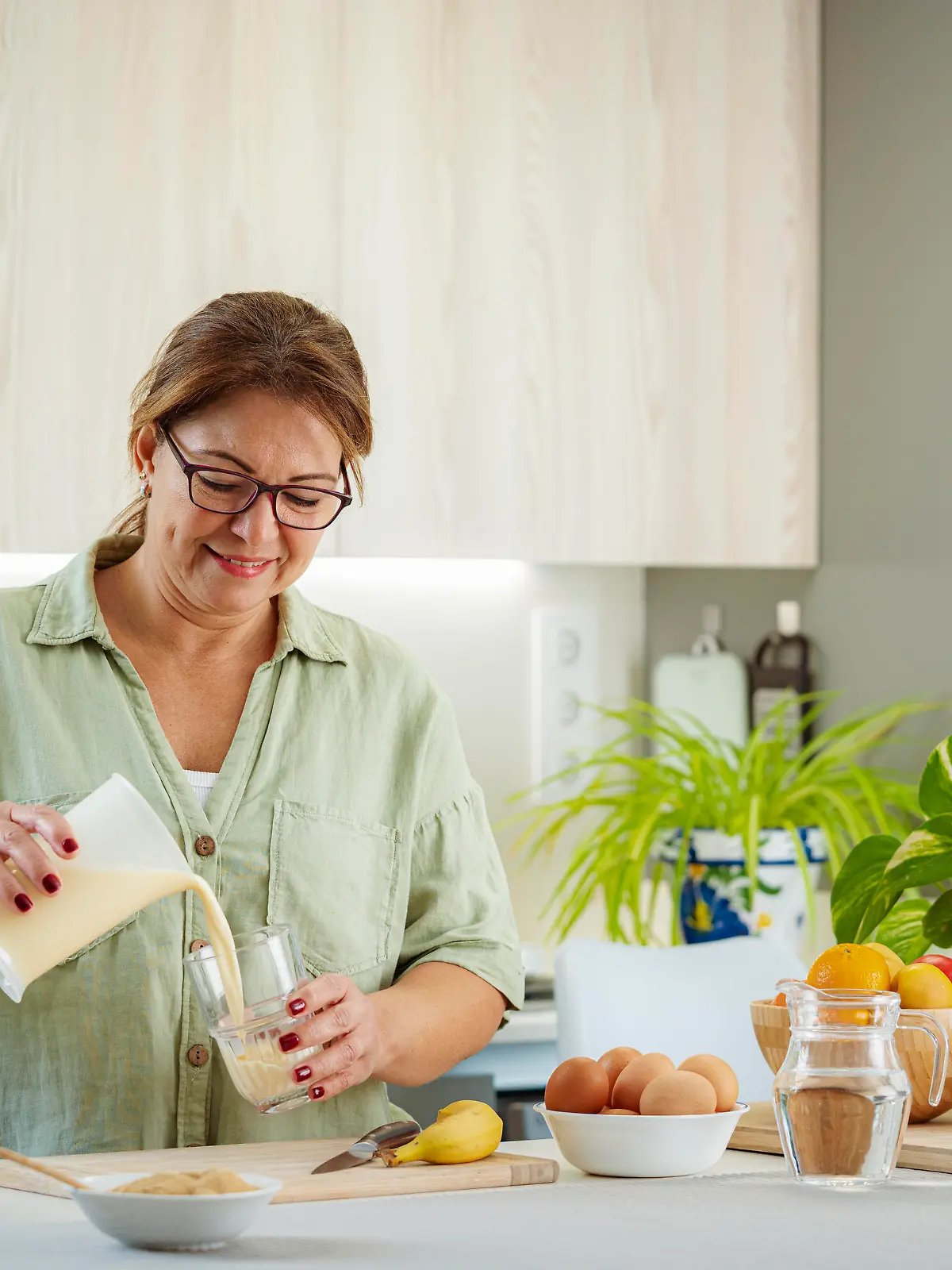 Mature woman pouring fresly blended protein and fruits drink