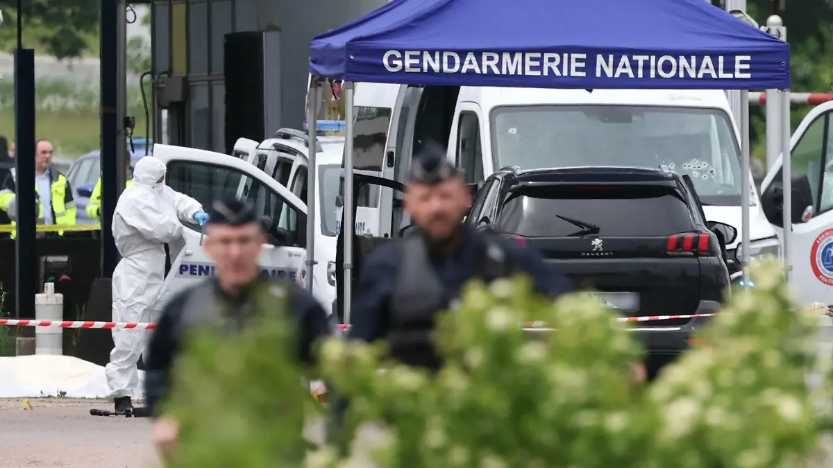 14.05.2024, Frankreich, Incarville: Ein Gerichtsmediziner arbeitet, während Polizisten am Ort eines Rammangriffs patrouillieren, der sich am späten Vormittag an einer Mautstelle in Incarville in der nordfranzösischen Region Eure ereignete. Bei einem Überfall auf einen Gefangenentransport im Norden Frankreichs seien Polizisten getötet und weitere verletzt worden. Foto: Alain Jocard/AFP/dpa +++ dpa-Bildfunk +++