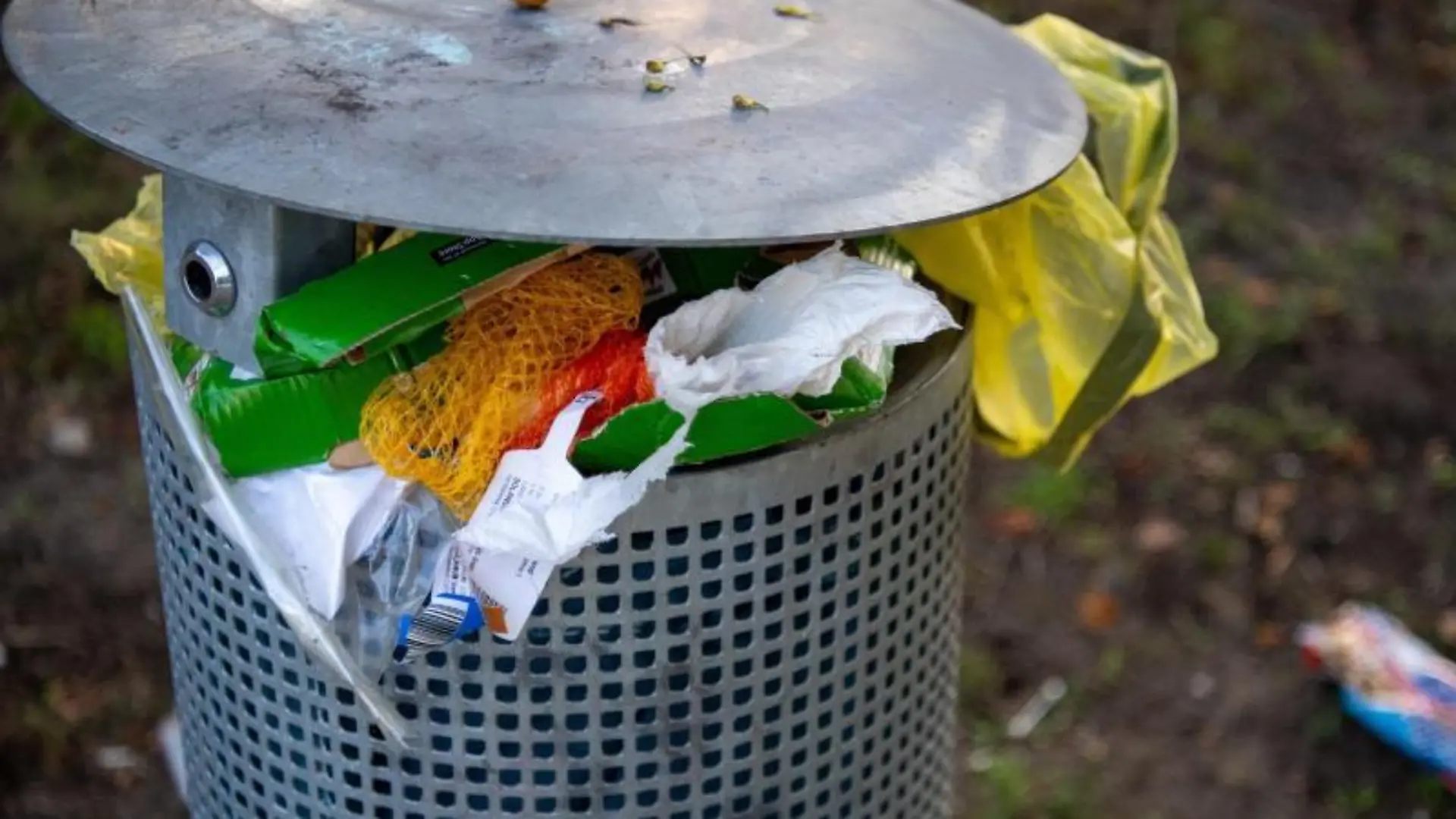 Ein überfüllter Mülleimer steht in einem Park