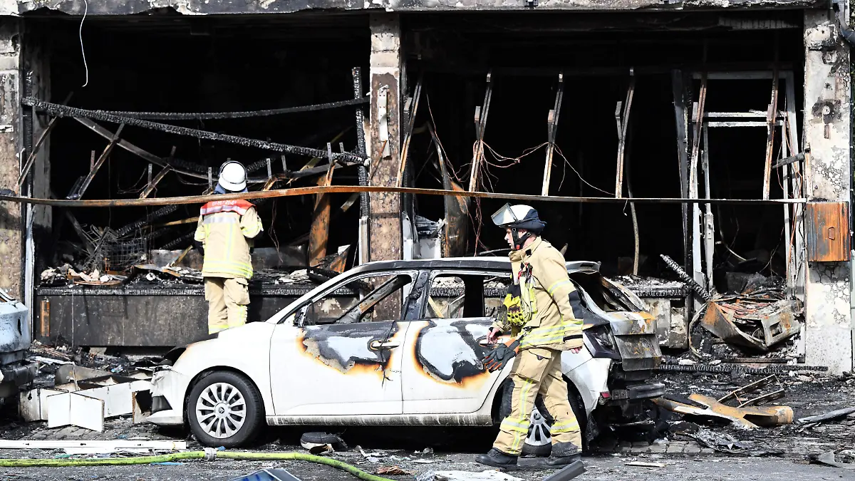 Einsatzkräfte der Feuerwehr besichtigen Trümmer vor einem Wohnhaus, in dem ein Brand wütete. Bei dem Brand in Düsseldorf sind mehrere Menschen ums Leben gekommen und weitere verletzt worden. Wie die Feuerwehr mitteilte, war in der Nacht zum Donnerstag aus bislang ungeklärter Ursache ein in einem Wohnhaus integrierter Kiosk in Brand geraten.