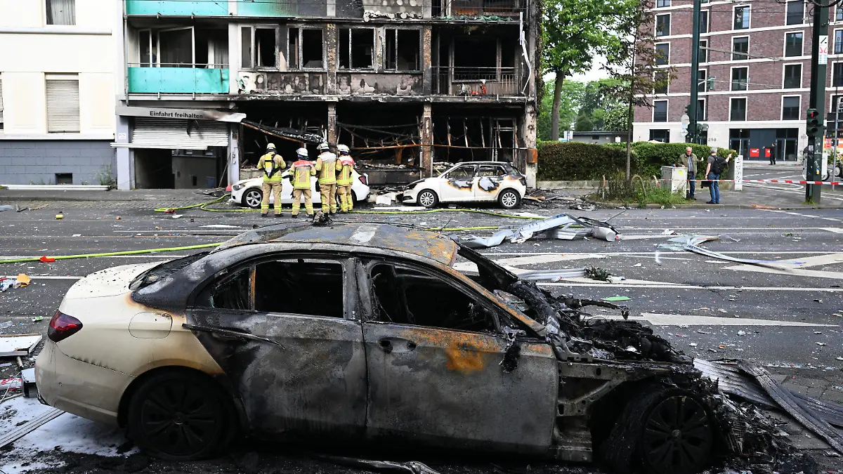 16.05.2024, Nordrhein-Westfalen, Düsseldorf: Ein ausgebranntes Auto steht vor einem Wohnhaus, in dem ein Brand wütete. Bei dem Brand in Düsseldorf sind mehrere Menschen ums Leben gekommen und weitere verletzt worden. Wie die Feuerwehr mitteilte, war in der Nacht zum Donnerstag aus bislang ungeklärter Ursache ein in einem Wohnhaus integrierter Kiosk in Brand geraten. Foto: Federico Gambarini/dpa +++ dpa-Bildfunk +++