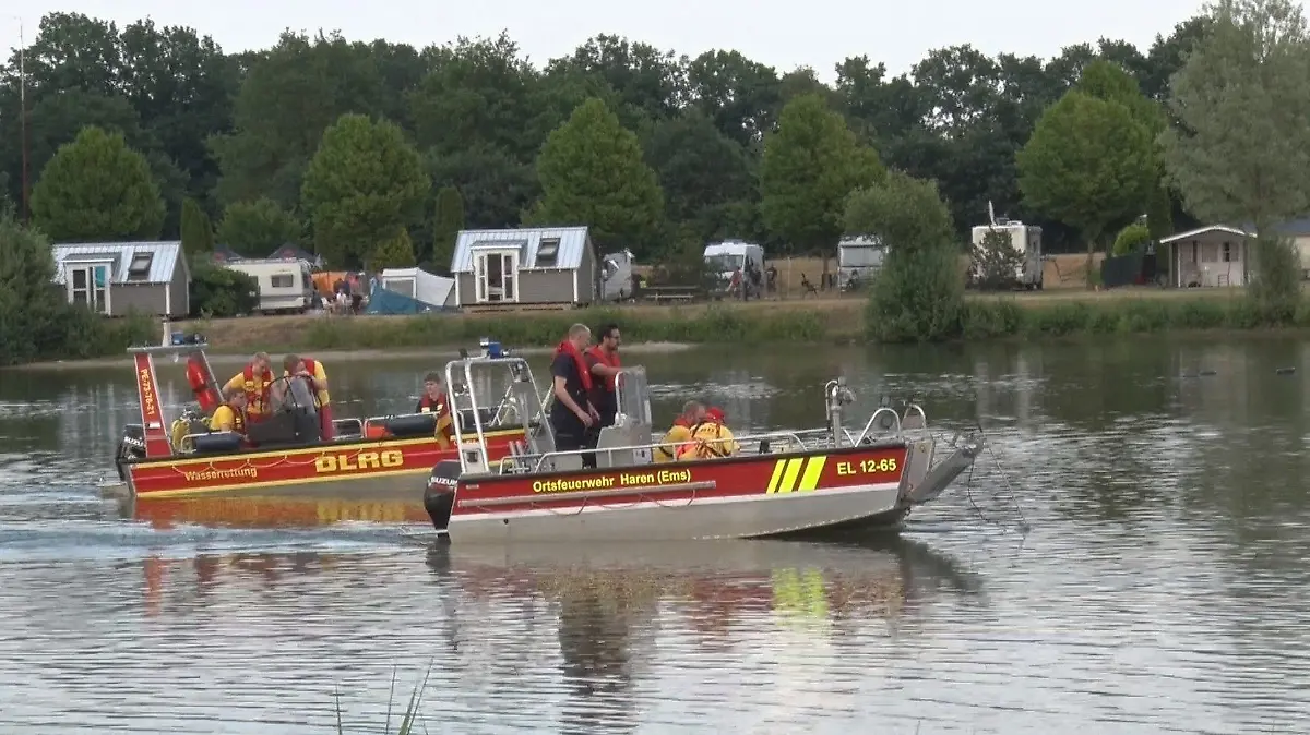 24.06.2023, Niedersachsen, Twist: Mitglieder von DLRG und Feuerwehr suchen einen See an einem Campingplatz mit Booten ab. Bei einem Badeunfall im Landkreis Emsland ist ein 32 Jahre alter Mann ums Leben gekommen. Er ertrank am Samstag in einem See an einem Campingplatz in Twist, wie ein Sprecher der Polizei am frühen Sonntagmorgen mitteilte. Weitere Details waren zunächst nicht bekannt. Foto: NWM-TV/dpa +++ dpa-Bildfunk +++