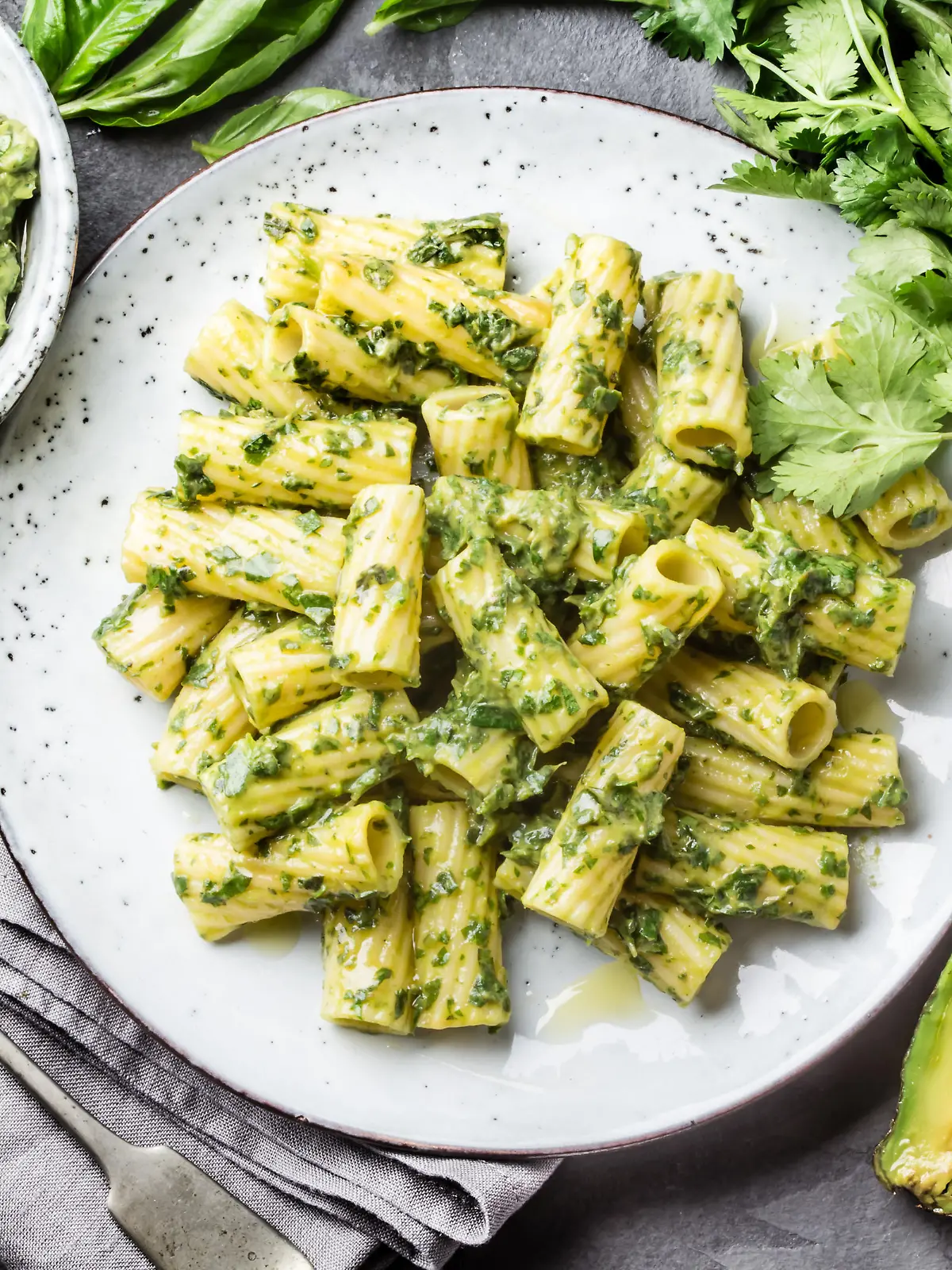 Vegetarian green pasta with avocado and herbs sauce on slate background