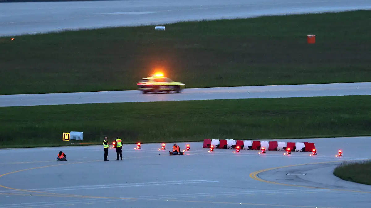 18.05.2024, Bayern, München: Klimaaktivisten haben sich am frühen Morgen auf einer Zufahrt für Start- und Landebahnen am Flughafen Franz-Josef-Strauß festgeklebt. Klimaschutzaktivisten haben am frühen Samstagmorgen den Münchner Flughafen lahmgelegt. Die Aktivisten waren in den inneren Bereich des Airport-Geländes gelangt. Mitglieder der sogenannten Letzten Generation hatten nach eigenen Angaben geplant, auf das Gelände des Flughafens zu gelangen, um mindestens eine der beiden Start- und Landebahnen zu blockieren. Foto: Karl-Josef Hildenbrand/dpa +++ dpa-Bildfunk +++