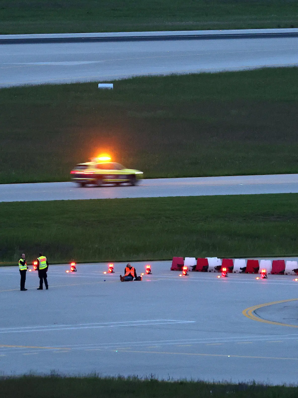 18.05.2024, Bayern, München: Klimaaktivisten haben sich am frühen Morgen auf einer Zufahrt für Start- und Landebahnen am Flughafen Franz-Josef-Strauß festgeklebt. Klimaschutzaktivisten haben am frühen Samstagmorgen den Münchner Flughafen lahmgelegt. Die Aktivisten waren in den inneren Bereich des Airport-Geländes gelangt. Mitglieder der sogenannten Letzten Generation hatten nach eigenen Angaben geplant, auf das Gelände des Flughafens zu gelangen, um mindestens eine der beiden Start- und Landebahnen zu blockieren. Foto: Karl-Josef Hildenbrand/dpa +++ dpa-Bildfunk +++