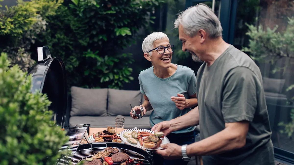 Senior couple preparing barbecue at the backyard.