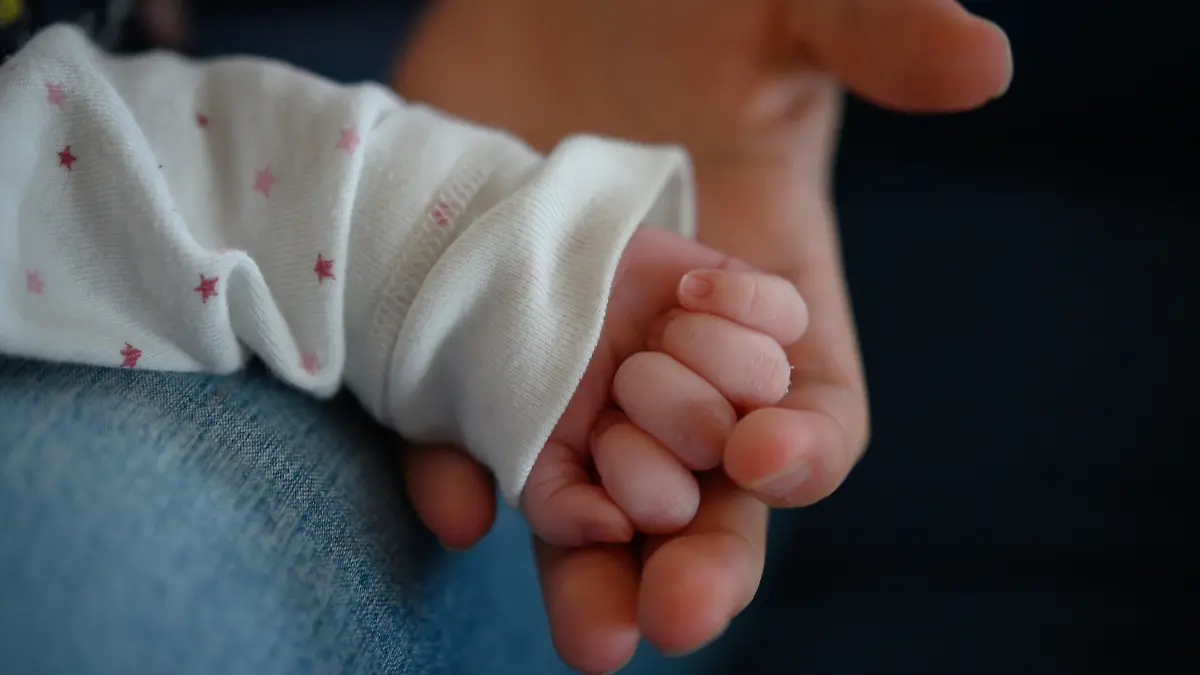 ARCHIV - 02.02.2020, Baden-Württemberg, Stuttgart: Die Hand eines zwei Wochen altes Neugeborenen liegt in der Hand seiner Mutter. In Polen hat eine 13-jährige Schülerin auf einer Klassenfahrt ein Baby zur Welt gebracht. (zu dpa: «Polen: 13-Jährige bringt auf Klassenfahrt Kind zur Welt») Foto: Sebastian Gollnow/dpa +++ dpa-Bildfunk +++