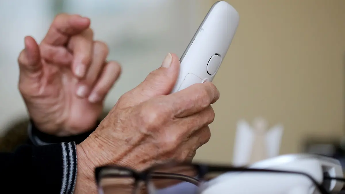 Eine ältere Dame nimmt in ihrer Wohnung ein Telefongespräch an.