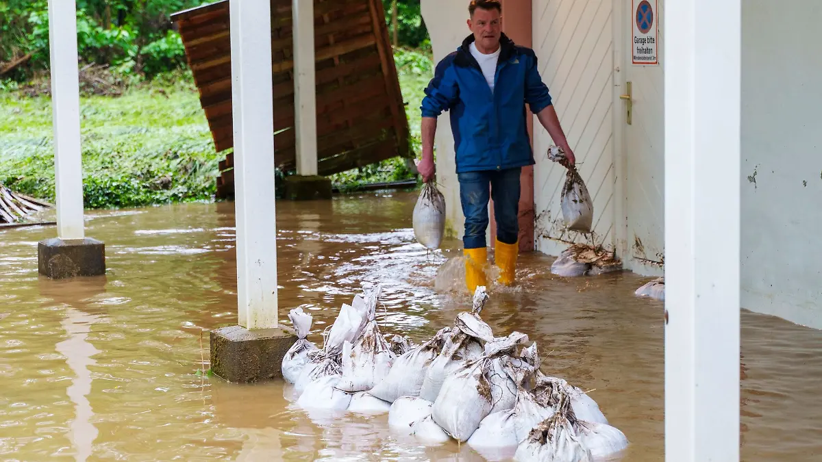 Der Betreiber eines Weingutes schleppt Sandsäcke.