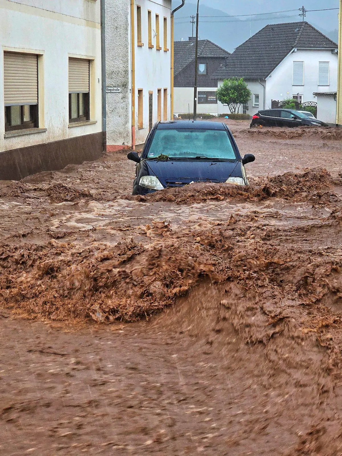 19.05.2024, Rheinland-Pfalz, Kirn: Ein Auto bahnt sich den Weg durch die Wassermassen. Extremer Starkregen hat am Sonntagnachmittag in der rheinland-pfälzischen Stadt Kirn zu Überflutungen und Erdrutschen geführt. Foto: Sebastian Schmitt/dpa +++ dpa-Bildfunk +++