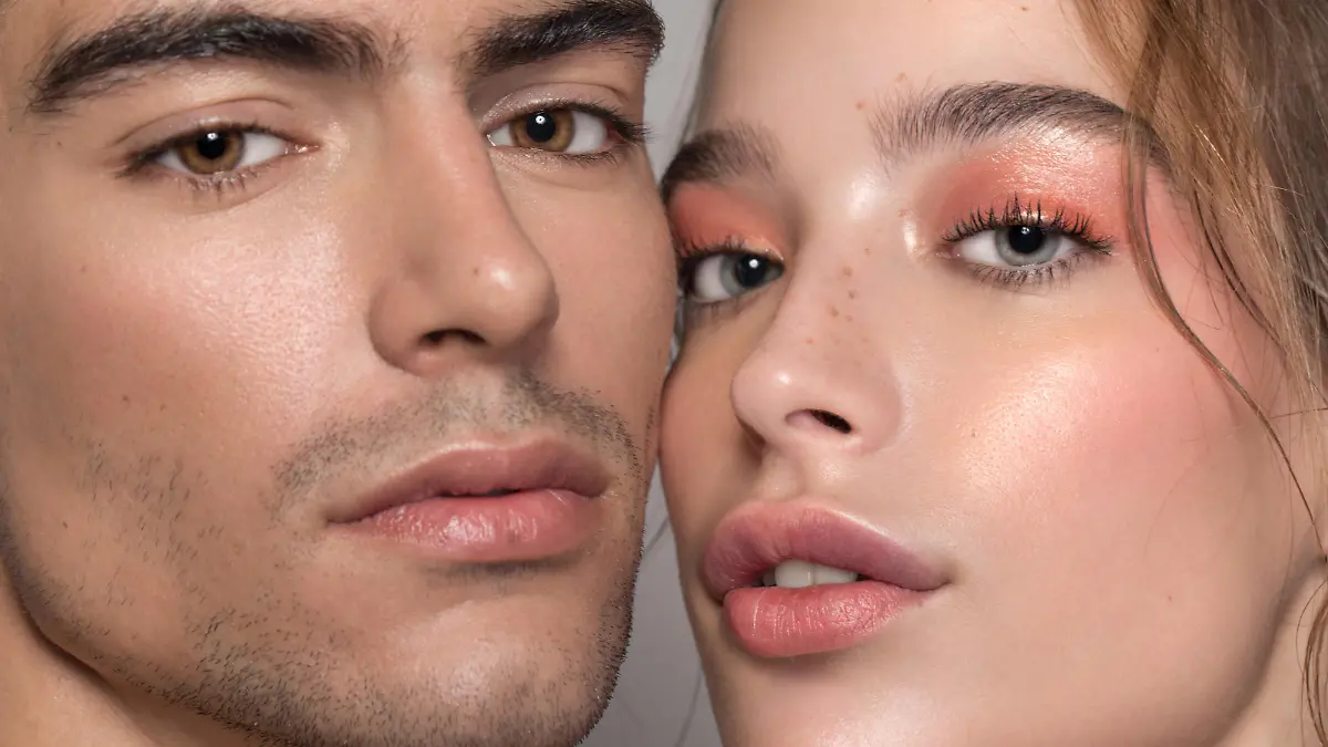 Closeup studio shot of a beautiful young woman and man with freckles skin posing against a grey background