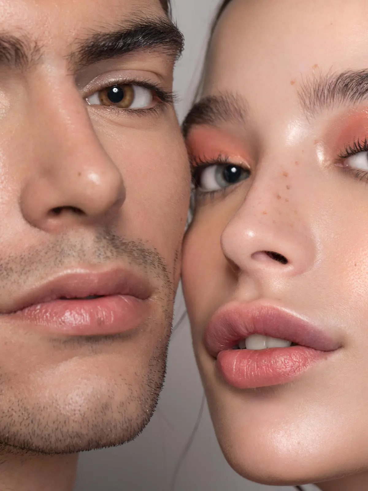 Closeup studio shot of a beautiful young woman and man with freckles skin posing against a grey background