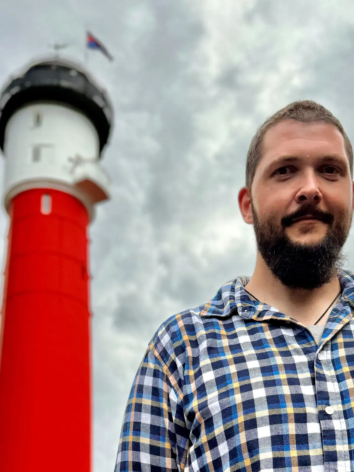 20.05.2024, Niedersachsen, Wangerooge: Daniel Jochheim, neuer Leuchtturmwärter auf der Nordseeinsel Wangerooge, steht vor dem denkmalgeschützten Alten Leuchtturm (gestellte Aufnahme). Ab Juni soll Jochheim seinen neuen Job in einem der Wahrzeichen der Insel antreten. Foto: Jörn Hüneke/dpa +++ dpa-Bildfunk +++