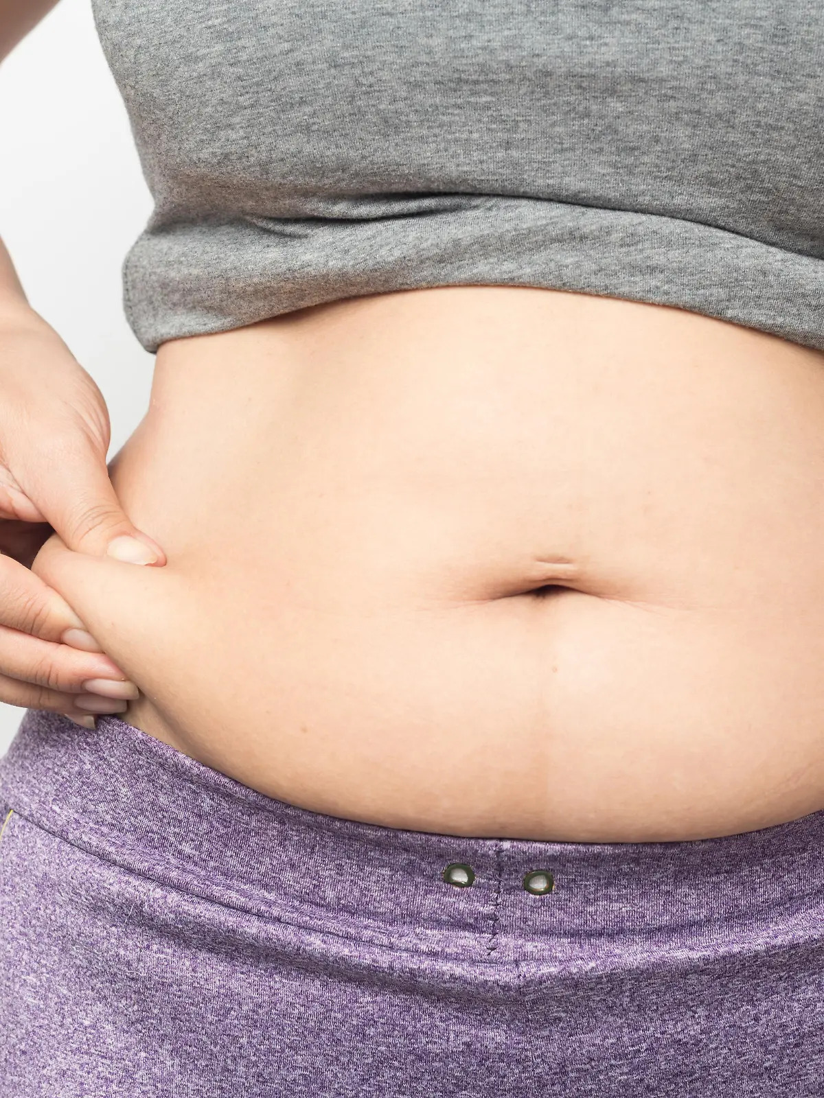 Overweight woman hand pinching excessive belly fat on gray background, Healthy concept