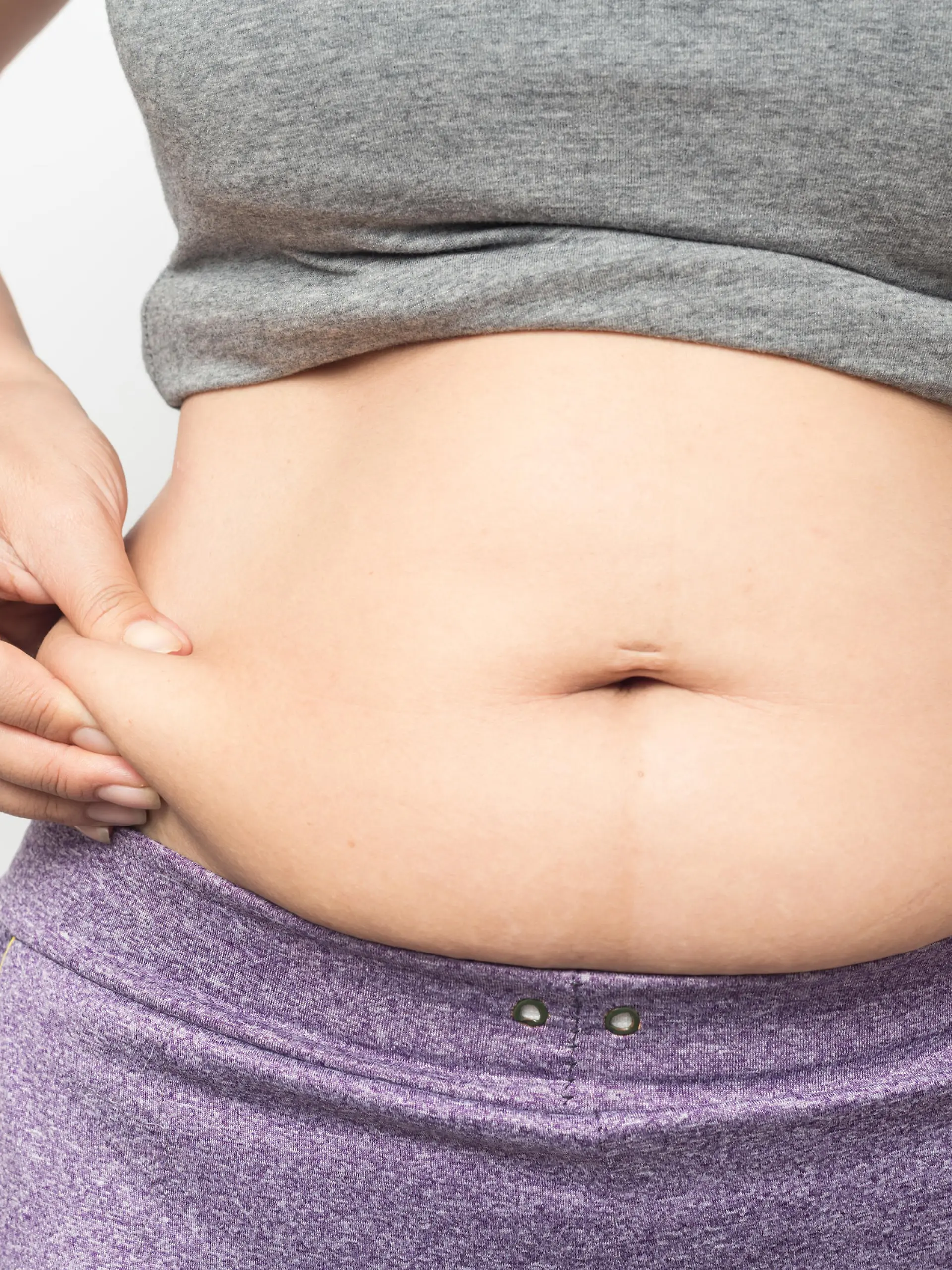 Overweight woman hand pinching excessive belly fat on gray background, Healthy concept