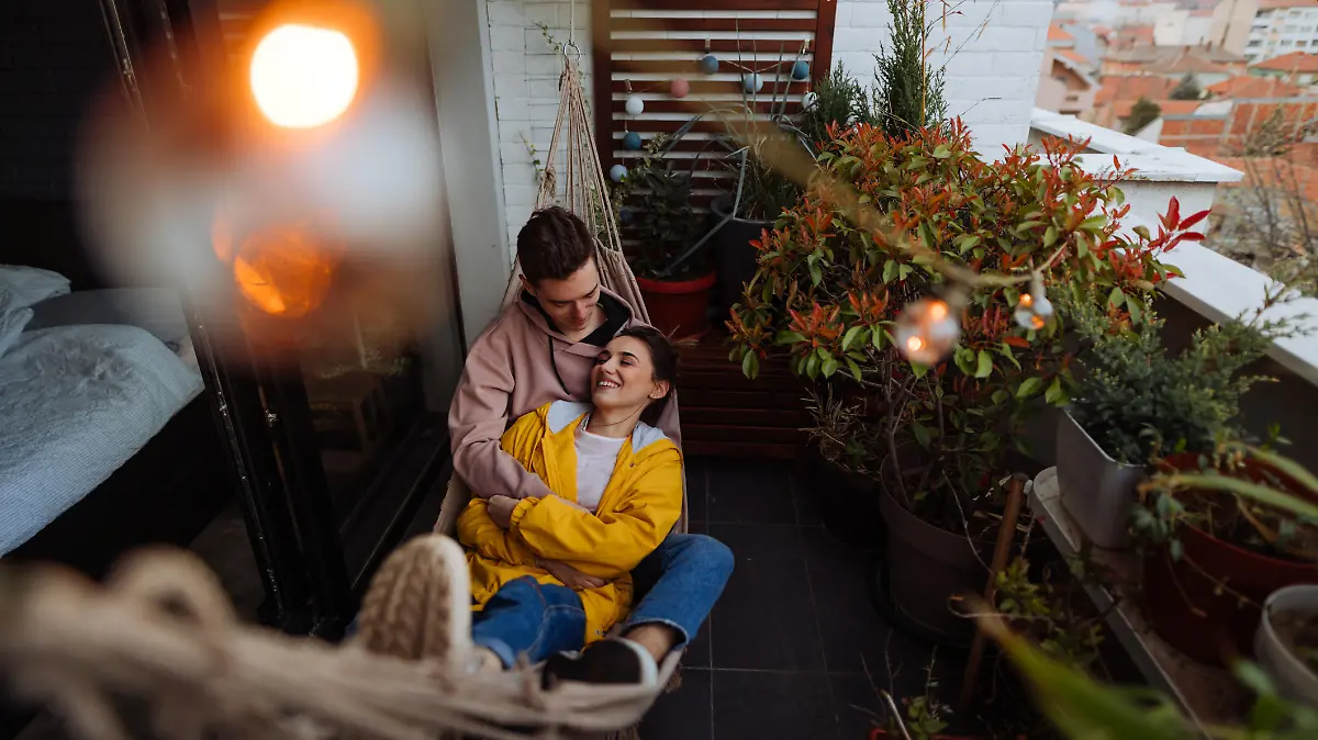 Photo of a young couple having a relaxing moment in a hammock on a terrace of their apartment