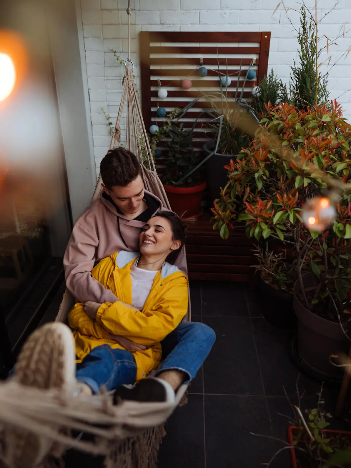 Photo of a young couple having a relaxing moment in a hammock on a terrace of their apartment