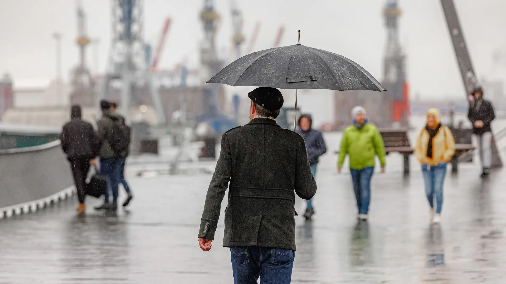 ARCHIV - 23.12.2023, Hamburg: Menschen gehen bei Nieselregen auf dem Hochwasserschutzbauwerk am Baumwall in Hamburg spazieren. (zu dpa: «Regnerisches Wetter zum Wochenstart im Norden») Foto: Markus Scholz/dpa +++ dpa-Bildfunk +++