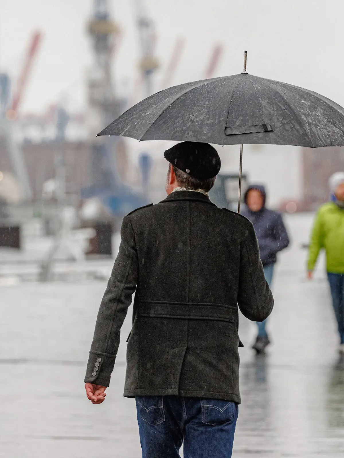 ARCHIV - 23.12.2023, Hamburg: Menschen gehen bei Nieselregen auf dem Hochwasserschutzbauwerk am Baumwall in Hamburg spazieren. (zu dpa: «Regnerisches Wetter zum Wochenstart im Norden») Foto: Markus Scholz/dpa +++ dpa-Bildfunk +++
