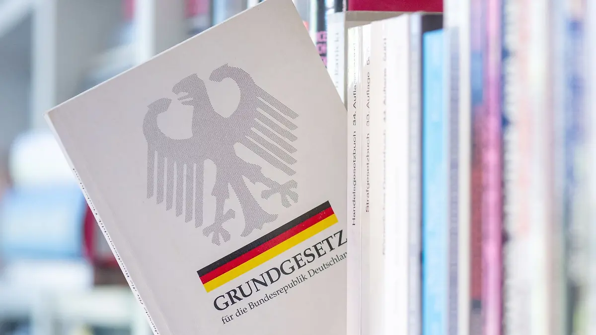 Ein Grundgesetz steckt in einem Bücherregal.