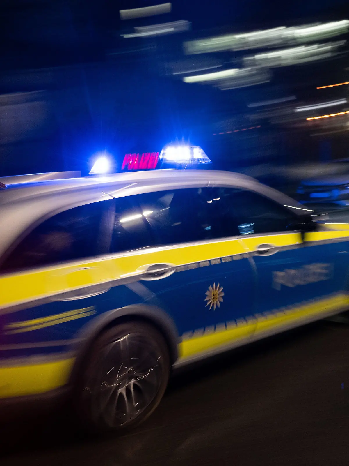 ILLUSTRATION - 30.11.2023, Baden-Württemberg, Stuttgart: Ein Polizeifahrzeug fährt im Rahmen mit Blaulicht an einem Gebäude vorbei (gestellte Szene, Langzeitblichtung mit Wischeffekt). (zu dpa: «Auto erfasst Kind an Bushaltestelle - Achtjähriger schwer verletzt») Foto: Marijan Murat/dpa +++ dpa-Bildfunk +++