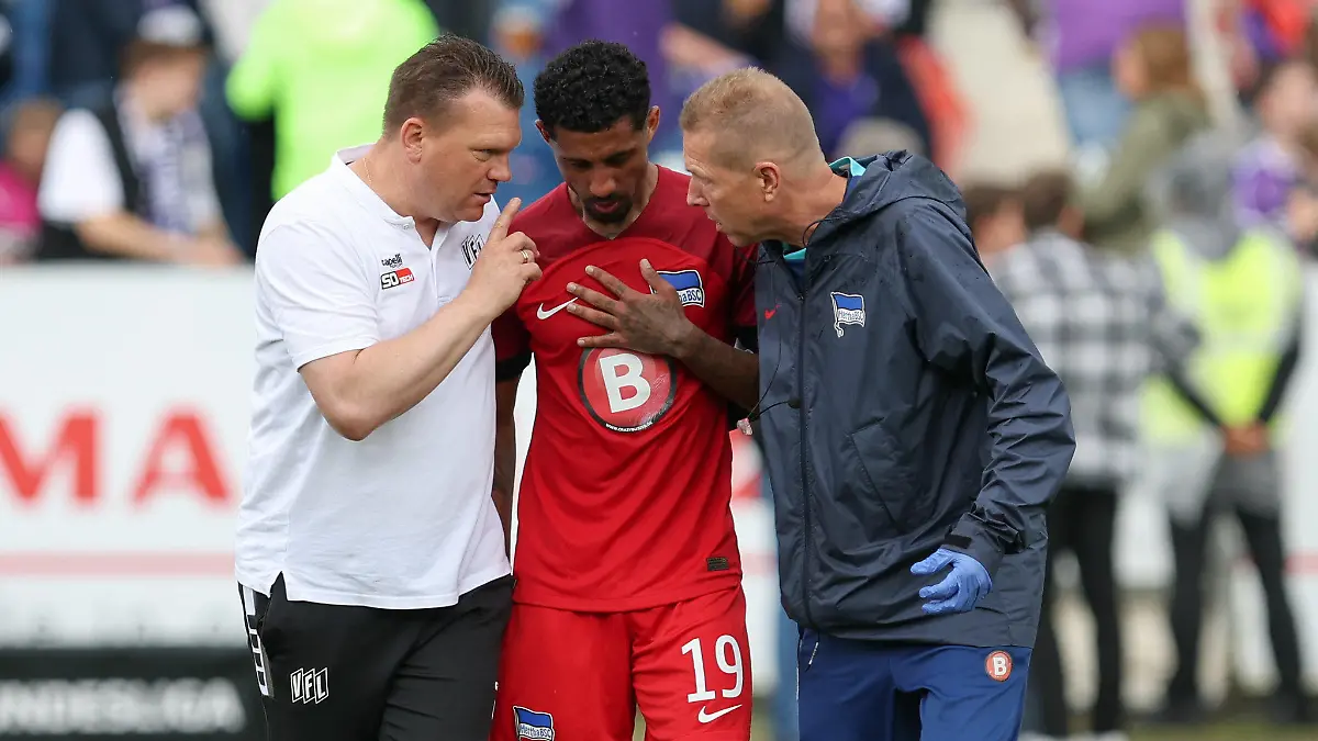 19.05.2024, Niedersachsen, Osnabrück: Fußball: 2. Bundesliga, VfL Osnabrück - Hertha BSC, 34. Spieltag im Stadion an der Bremer Brücke. Osnabrücks Trainer Uwe Koschinat (l) spricht mit Herthas Jeremy Dudziak (M). Foto: Friso Gentsch/dpa - WICHTIGER HINWEIS: Gemäß den Vorgaben der DFL Deutsche Fußball Liga bzw. des DFB Deutscher Fußball-Bund ist es untersagt, in dem Stadion und/oder vom Spiel angefertigte Fotoaufnahmen in Form von Sequenzbildern und/oder videoähnlichen Fotostrecken zu verwerten bzw. verwerten zu lassen. +++ dpa-Bildfunk +++