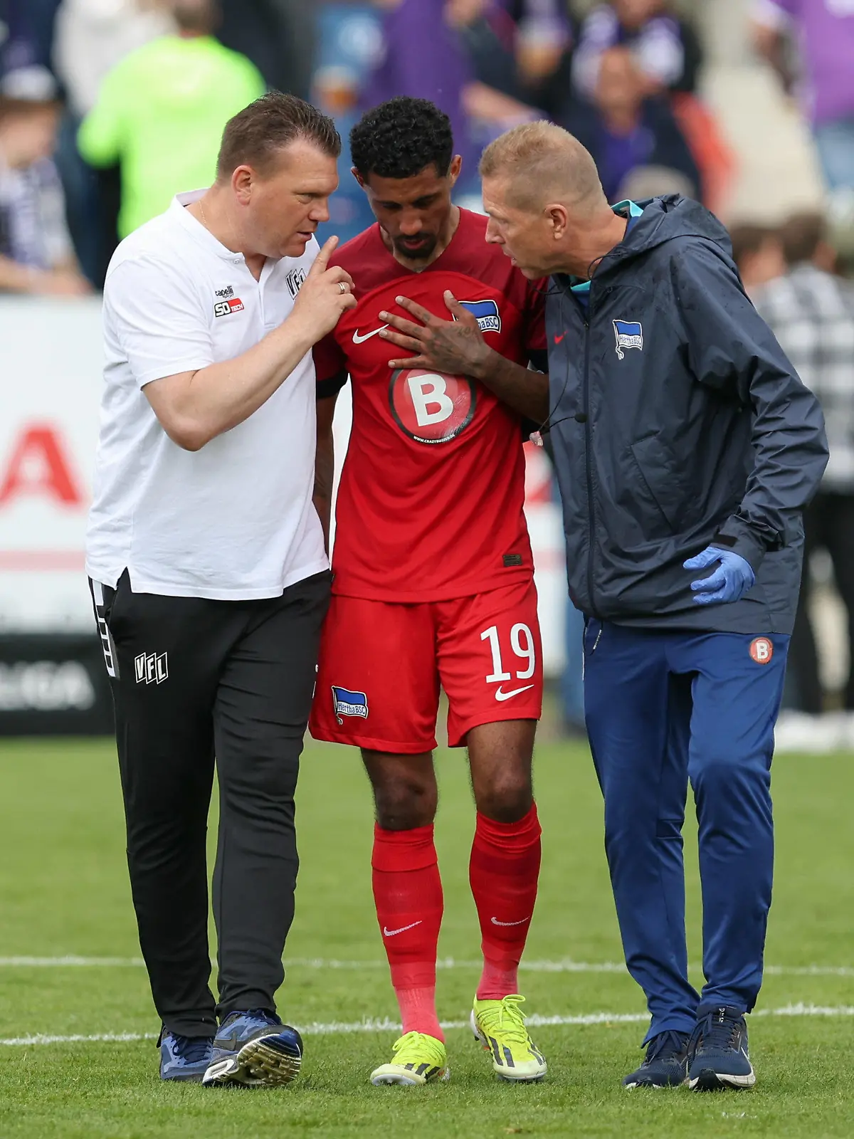 19.05.2024, Niedersachsen, Osnabrück: Fußball: 2. Bundesliga, VfL Osnabrück - Hertha BSC, 34. Spieltag im Stadion an der Bremer Brücke. Osnabrücks Trainer Uwe Koschinat (l) spricht mit Herthas Jeremy Dudziak (M). Foto: Friso Gentsch/dpa - WICHTIGER HINWEIS: Gemäß den Vorgaben der DFL Deutsche Fußball Liga bzw. des DFB Deutscher Fußball-Bund ist es untersagt, in dem Stadion und/oder vom Spiel angefertigte Fotoaufnahmen in Form von Sequenzbildern und/oder videoähnlichen Fotostrecken zu verwerten bzw. verwerten zu lassen. +++ dpa-Bildfunk +++