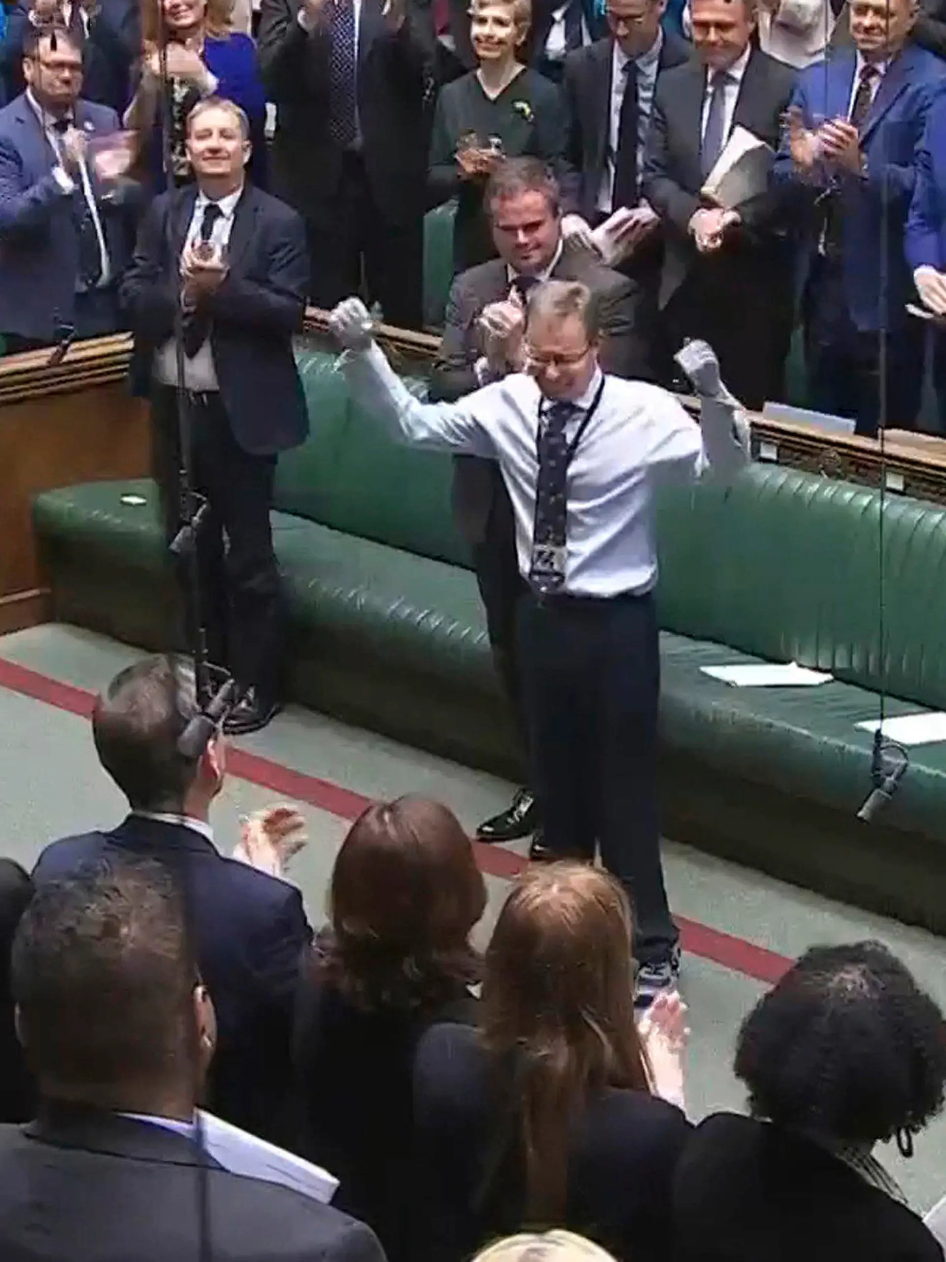 Craig Mackinlay, Conservative MP for South Thanet, is applauded by members of parliament as he returns to the House of Commons for the first time since he was rushed into hospital with sepsis on September 28, which left him with both of his hands and feet amputated, at the Parliament in London, Wednesday May 22, 2024. (House of Commons/UK Parliament via AP)