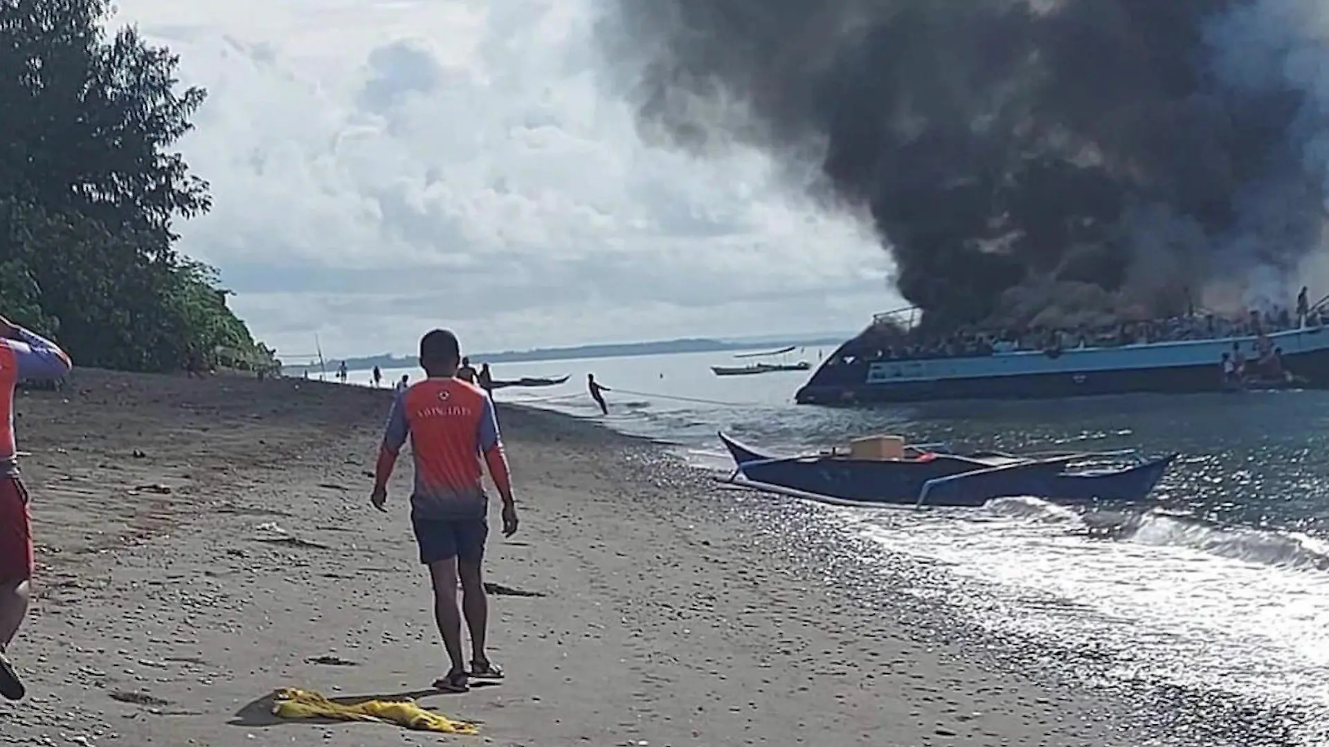 Mann läuft an Strand entlang. Brennende Fähre.