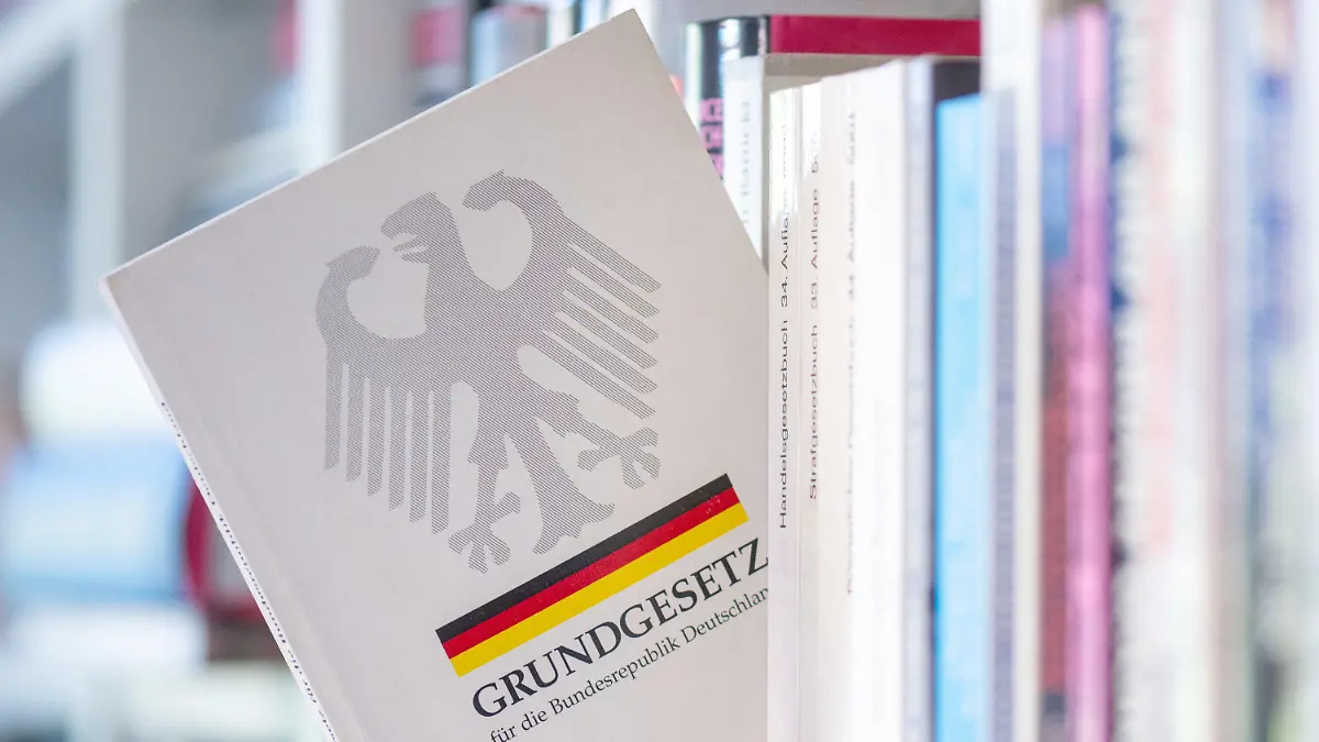 ARCHIV - 13.05.2024, Sachsen, Leipzig: ILLUSTRATION - Ein Grundgesetz steckt in einem Bücherregal. Das Grundgesetz der Bundesrepublik feiert in diesem Jahr seinen 75. Geburtstag. Es wurde am 23. Mai 1949 erlassen. (zu dpa: «Das Grundgesetz wird 75 - Staatsakt mit Rede Steinmeier») Foto: Hendrik Schmidt/dpa +++ dpa-Bildfunk +++
