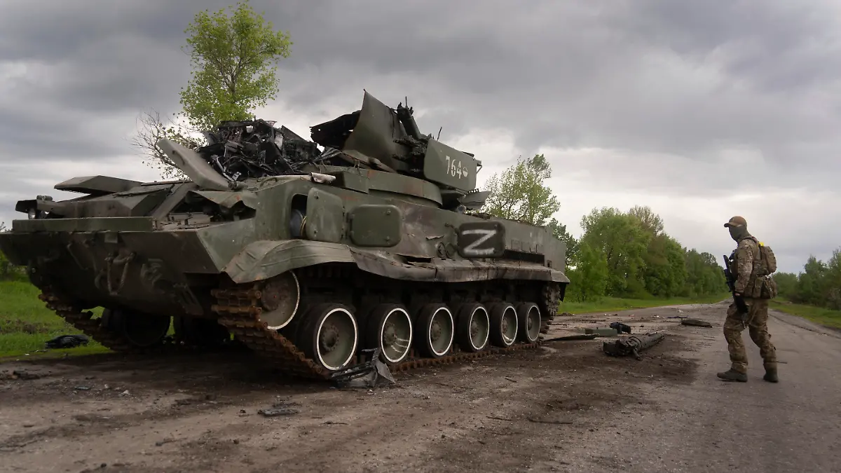 15.05.2022, Ukraine, Charkiw: Ein ukrainischer Soldat geht an einem zerstörten russischen APC Panzer in der Nähe von Kutusiwka, nördlich von Charkiw, im Osten der Ukraine, vorbei. Foto: Mstyslav Chernov/AP/dpa +++ dpa-Bildfunk +++