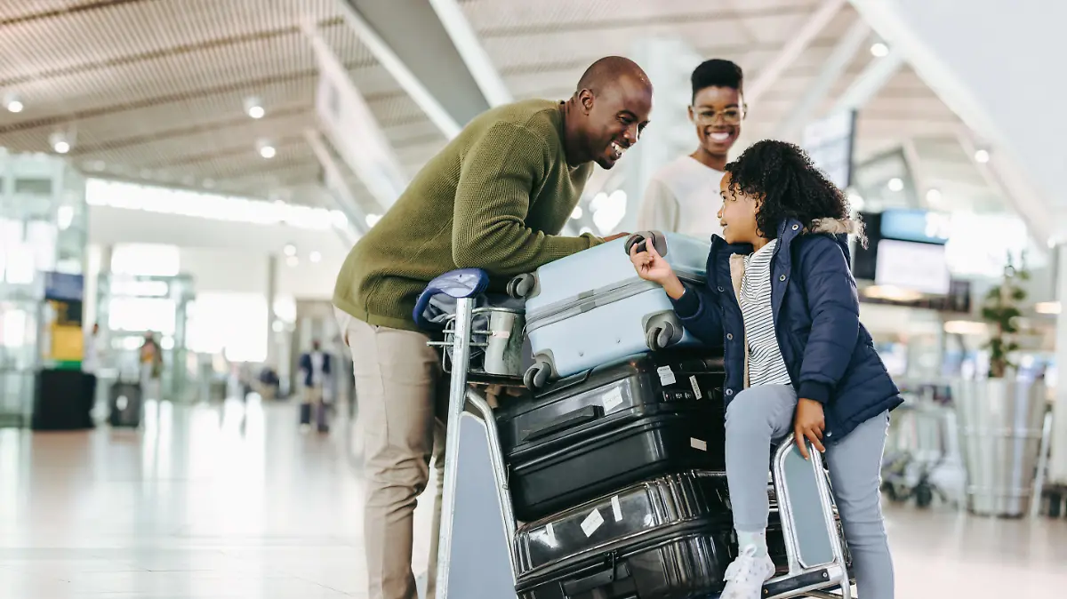 Father and mother waiting with young daughter at airport. Tourist family at airport terminal with luggage holiday.